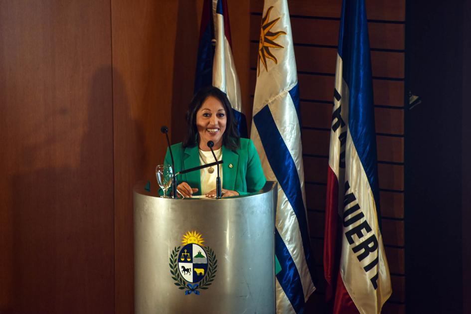 La ministra Fernanda Cardona cerró la primera jornada Cardona habla desde un atril; detrás, banderas