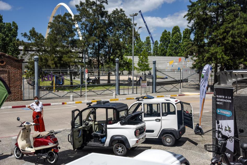 Triciclos blancos y moto roja; al lado de ellos, una empresaria