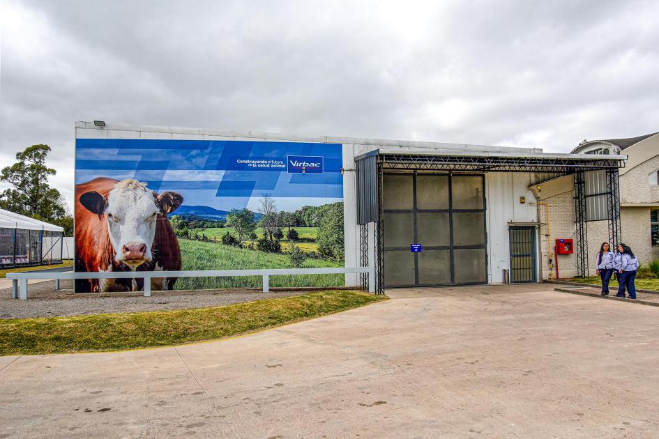 Exterior de la planta de Virbac Uruguay Exterior de la planta actual; se ve un gran cartel con vacas y el logo de la empresa; hay personas
