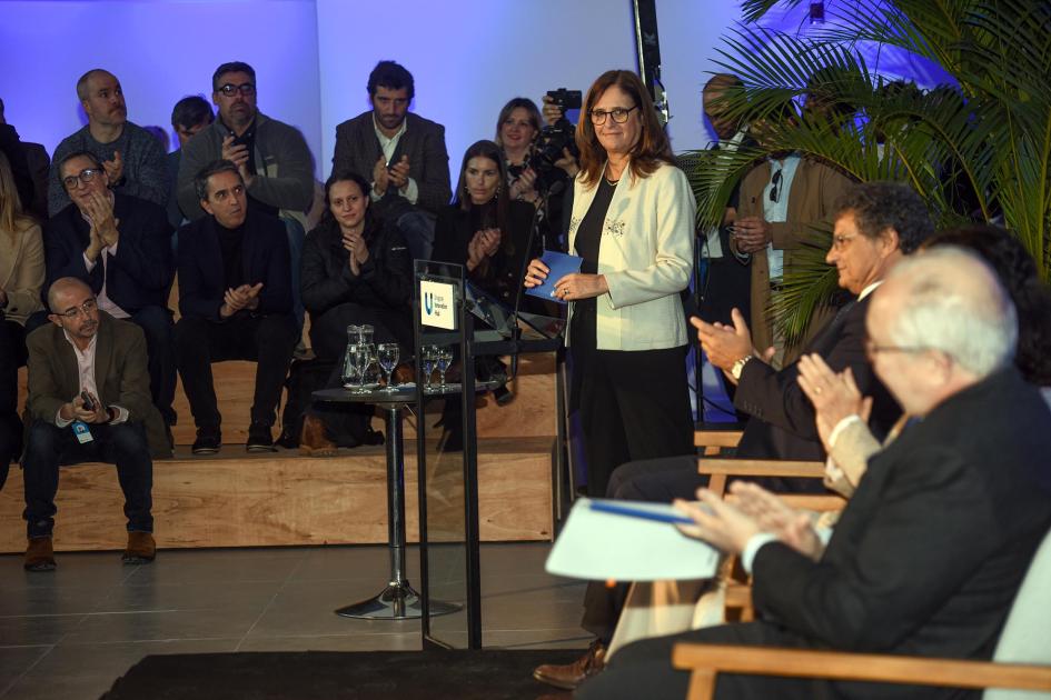 La ministra Elisa Facio destacó la importancia del nuevo campus Ministra Facio sonríe; la aplauden los ministros sentados en sillas, que se ven de espaldas