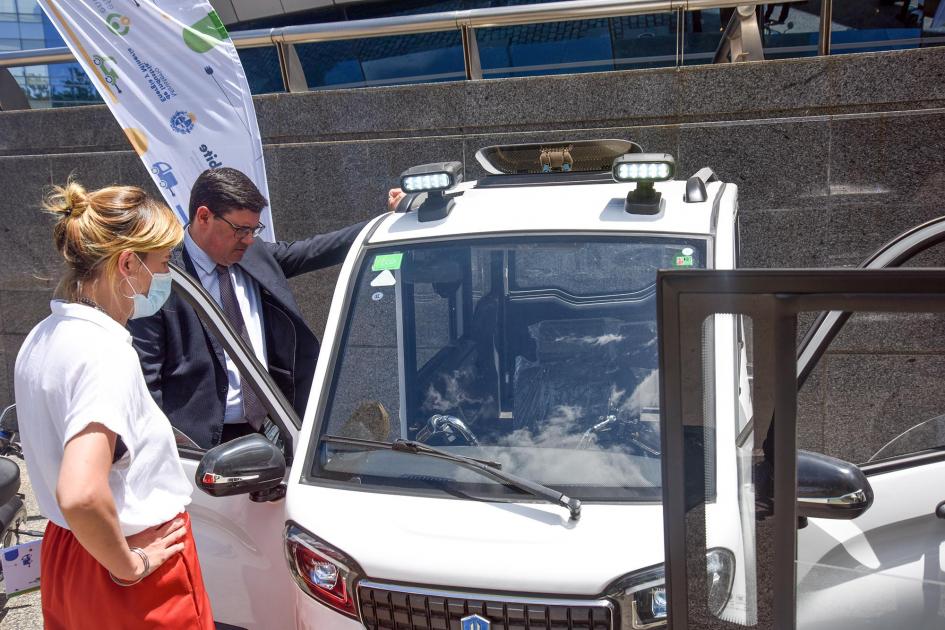 Autoridades conocieron los vehículos eléctricos Director Cantero dialoga con una empresaria junto a un triciclo eléctrico blanco