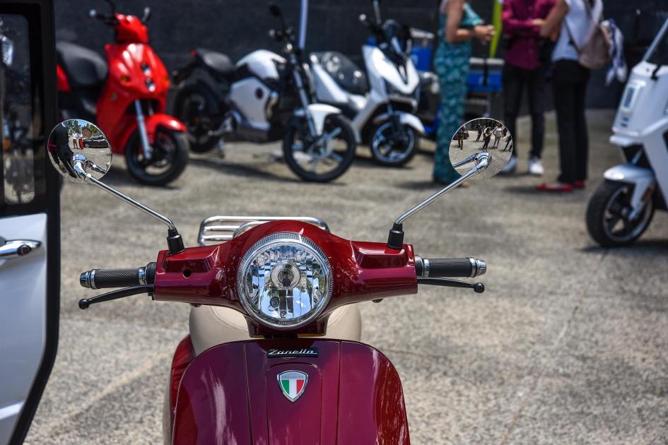 Vehículos eléctricos En primer plano, se ve una moto roja; al fondo, más motos de colores y un fragmento de un triciclo