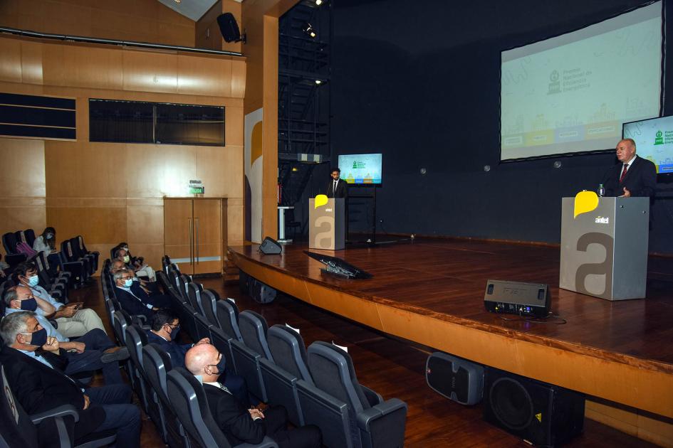 Escenario, con subsecretario Walter Verri hablando y pantallas detrás; y público frente a él