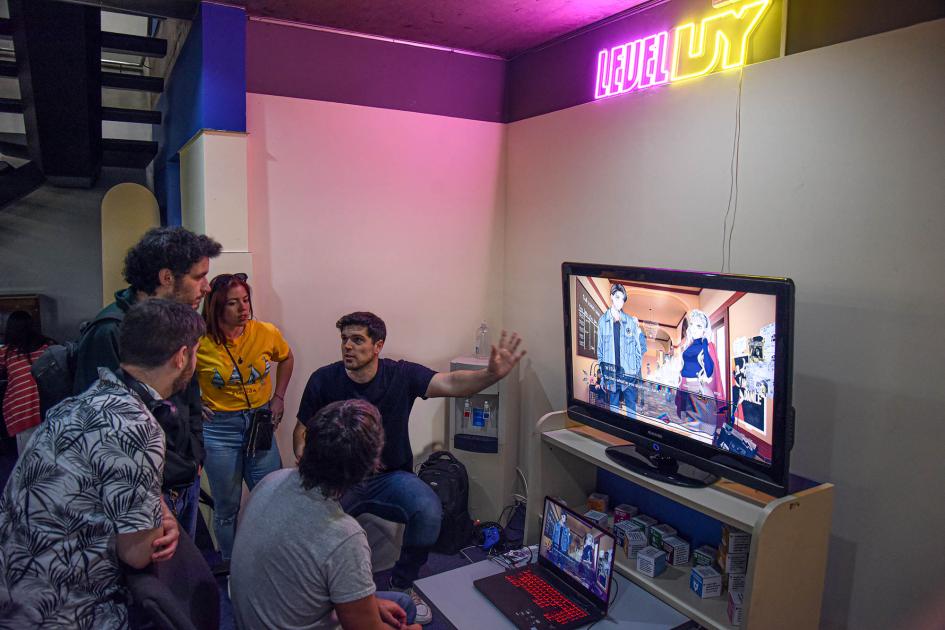 Personas alrededor de una pantalla con un videojuego y una laptop