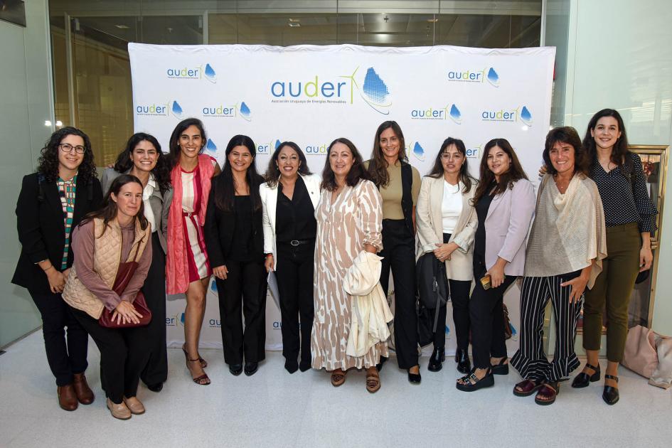 Grupo de mujeres participantes del encuentro; la ministra enfatizó su importancia para el sector Ministra y grupo de mujeres posan frente a un banner de AUDER