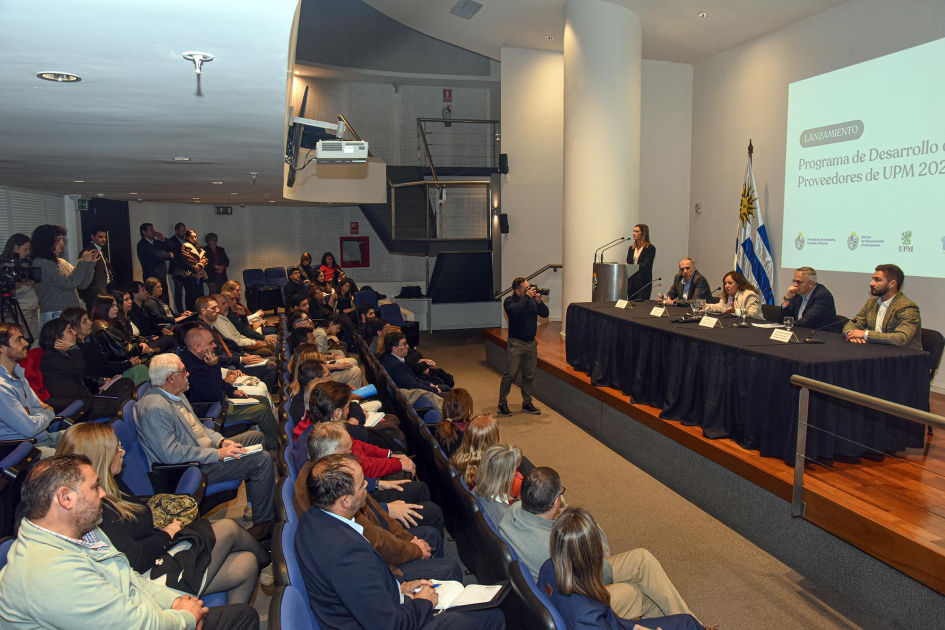 Lanzamiento del Programa de Desarrollo de Proveedores Nacionales de UPM 2026 Encima de un escenario, mesa de autoridades, maestra de ceremonias y pantalla; frente, público