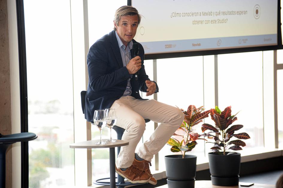 Rafael Staricco, de Quantik Un hombre habla, sentado, con un micrófono; detrás hay una pantalla