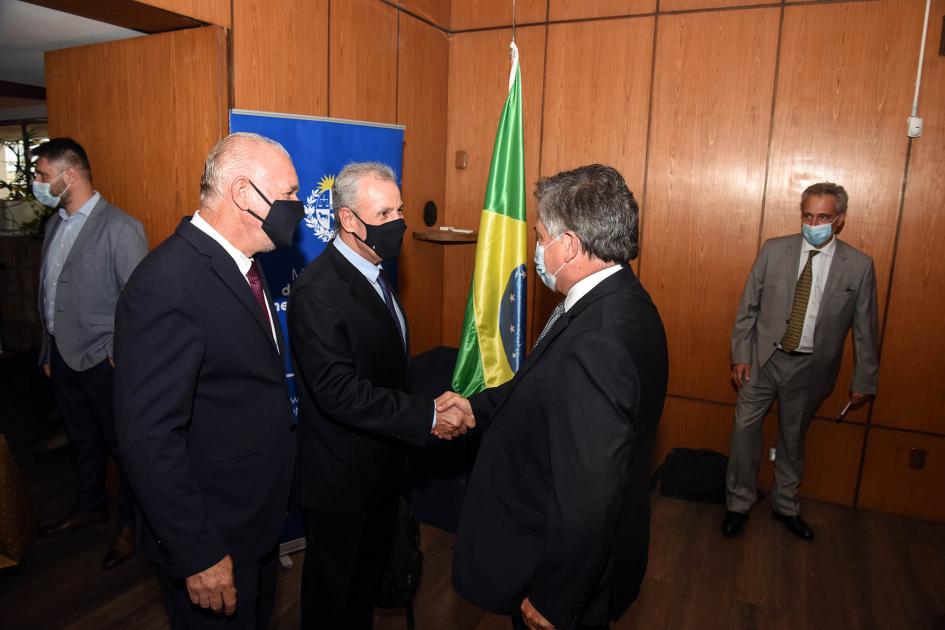 Los dos ministros se saludan, junto al subsecretario Verri; detrás está la bandera de Brasil