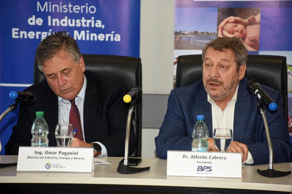 Alfredo Cabrera y Omar Paganini Cabrera habla en la mesa de autoriddades, junto a Paganini; detrás, banners