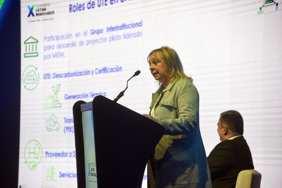 Presidenta de UTE habla desde un atril; detrás, Stipanicic, sentado