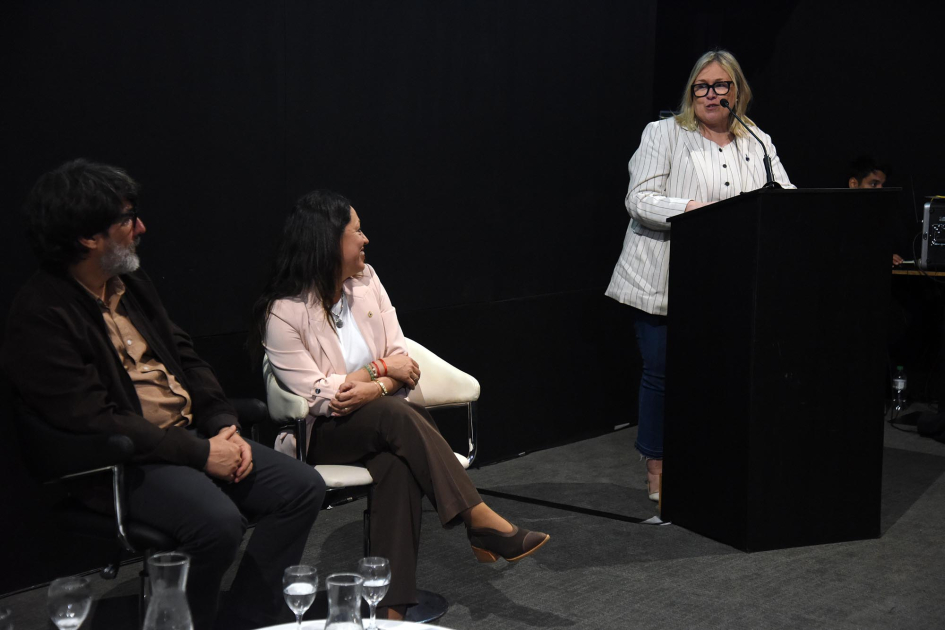 Autoridades en escenario Gisella Previtali habla desde atril. En el escenario, César Troncoso y Fernanda Cardona.