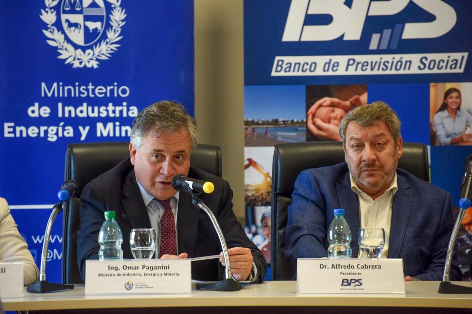 Paganini habla junto a Cabrera; detrás, banners del MIEM y el BPS