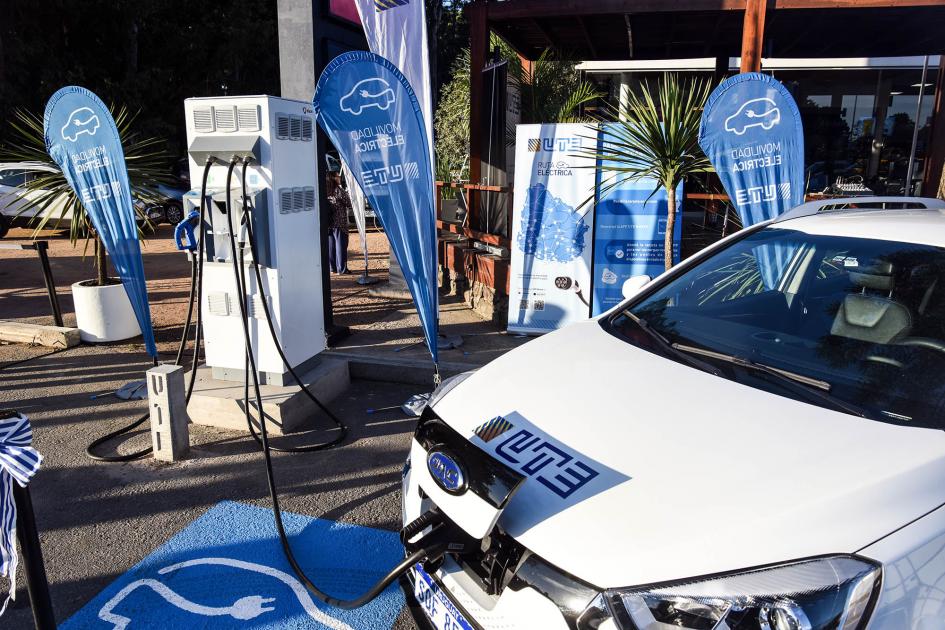 Punto de carga rápido Auto eléctrico de UTE conectado a un puesto de carga; detrás, banners de UTE