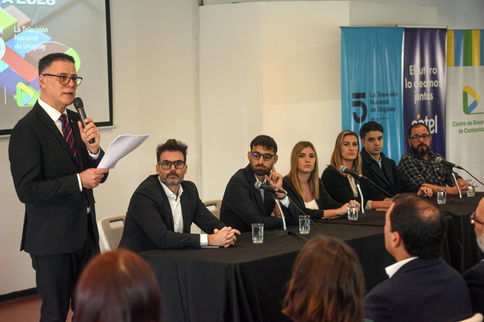 Director Pablo Siris en en lanzamiento de la programación de Medios Públicos para el Mundial FIFA Siris habla, de pie; periodistas, sentadas y sentados en mesa, frente al público