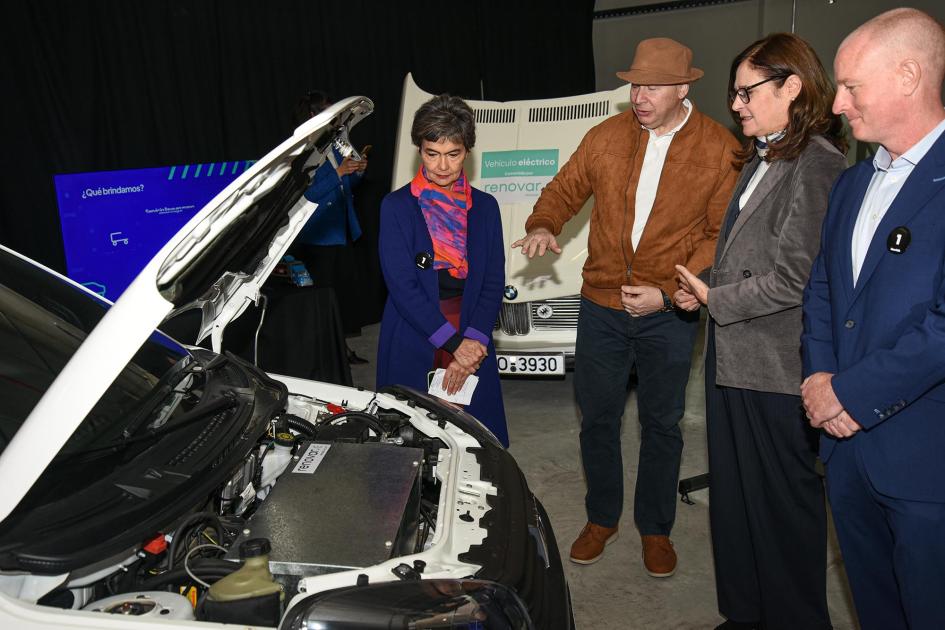 La ministra conoció los proyectos de las startups Ministra y otras personas escuchan a un emprendedor frente a un auto