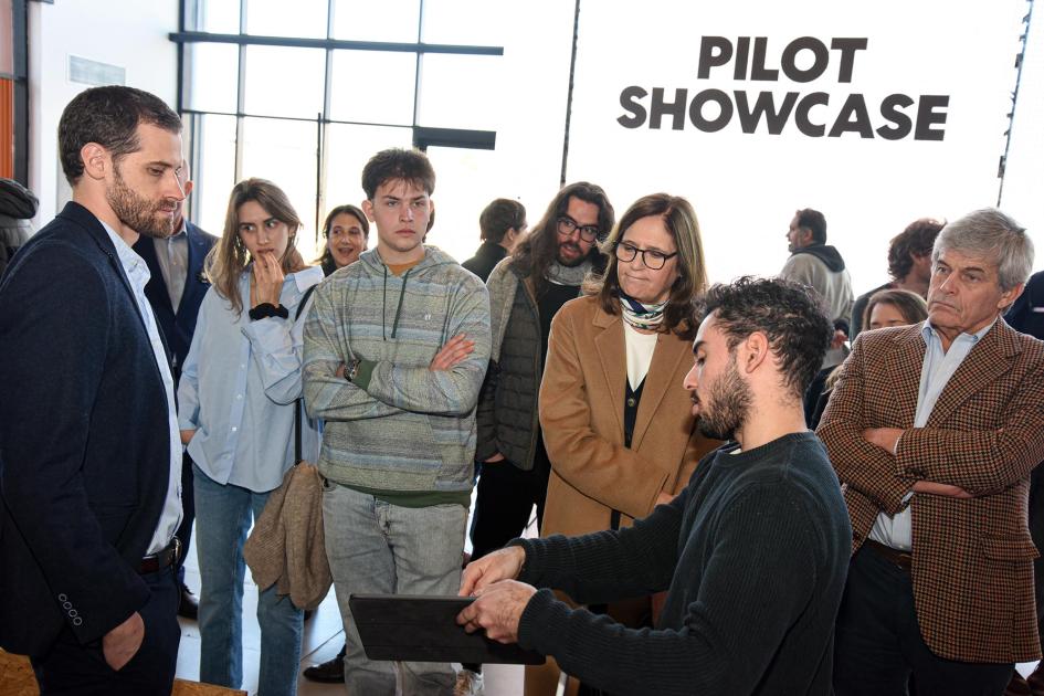 La ministra conoció los proyectos de las startups Ministra y otras personas observan a un representante de una startup; al fondo, nombre del evento