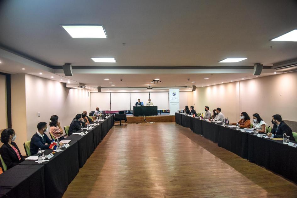 Participantes del evento Participantes del evento, sentados en mesas en "u" y vistos a distancia