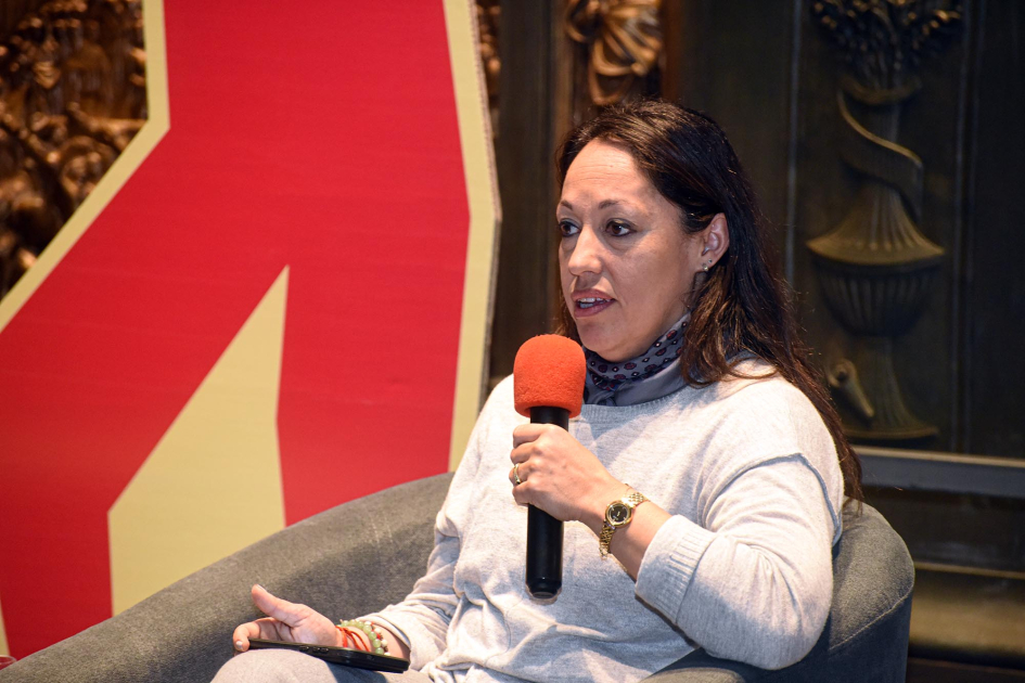 Ministra Cardona habla con un micrófono, sentada