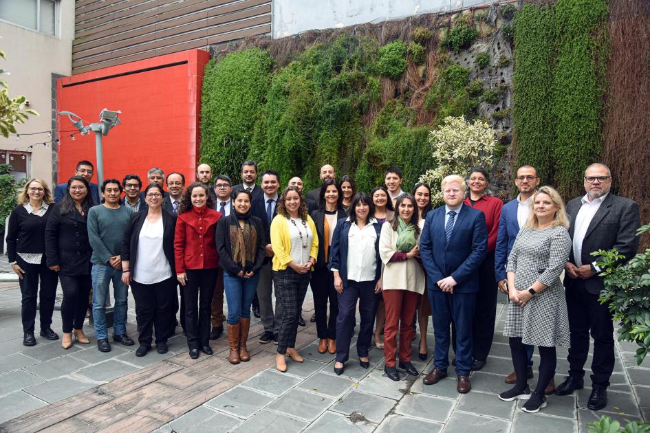 Foto grupal de los participantes Todos los representantes, en foto grupal, de pie, en un patio con plantas en la pared