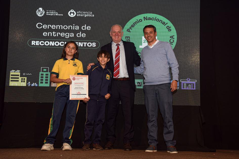 Representantes del Colegio Dámaso Antonio Larrañaga Dos niños y un adulto posan junto a Verri; detrás, una pantalla