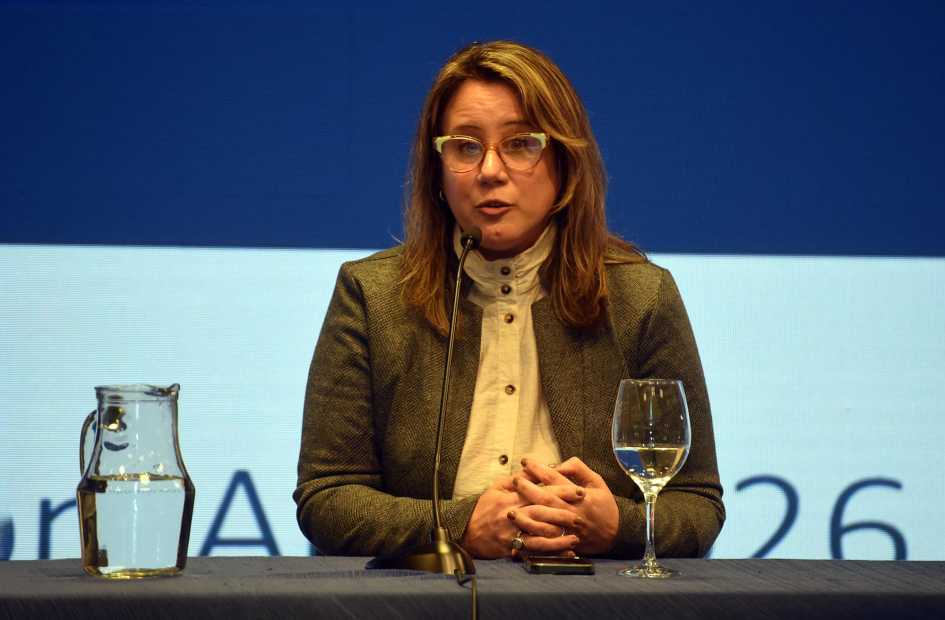 Carreto habla, sentada; detrás, pantalla