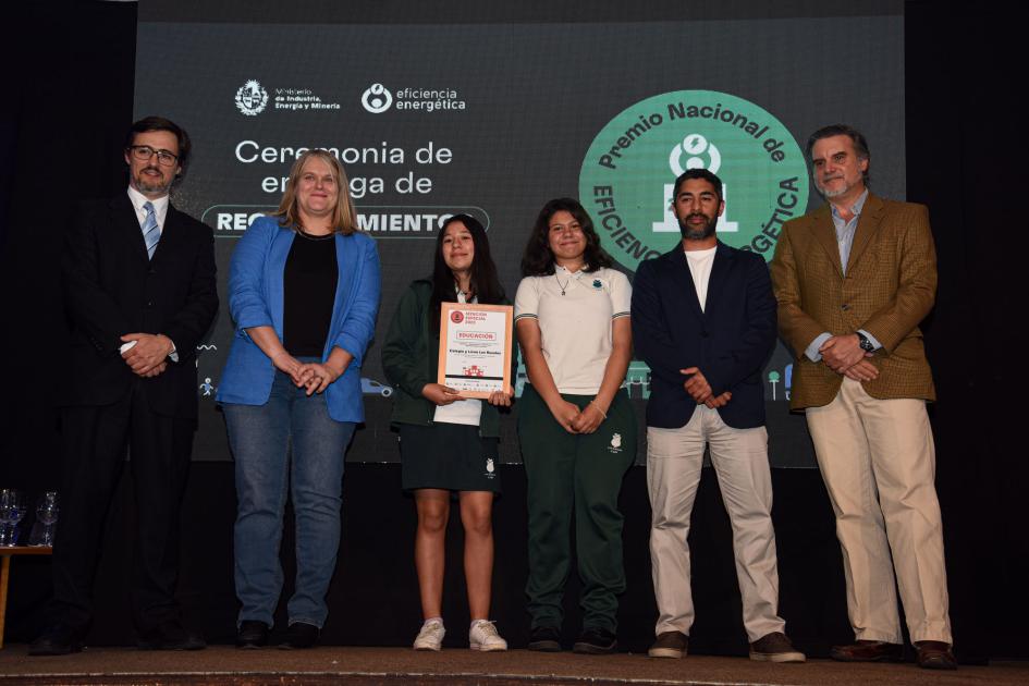 Tres hombres, una mujer y dos adolescentes de género femenino, que reciben la placa