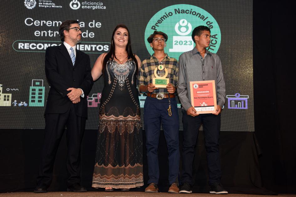 Una mujer, un hombre y dos adolescentes varones que sostienen la placa y el premio