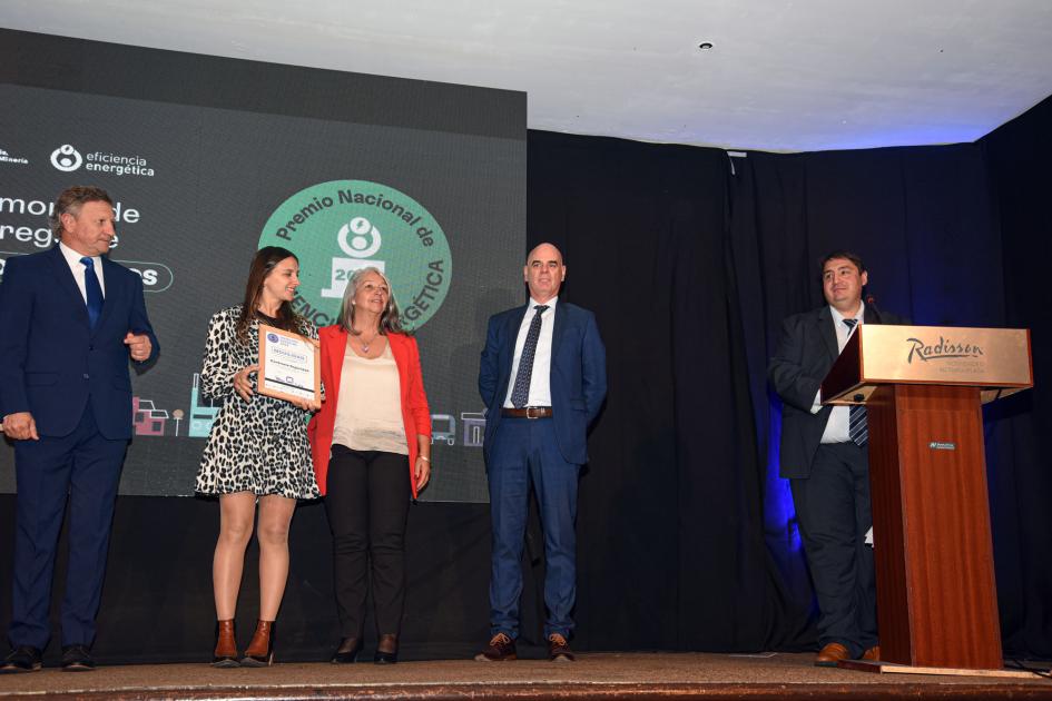 Representantes de Centinela Seguridad Tres hombres y dos mujeres; una de ellas sostiene una placa; un hombre está en un atril