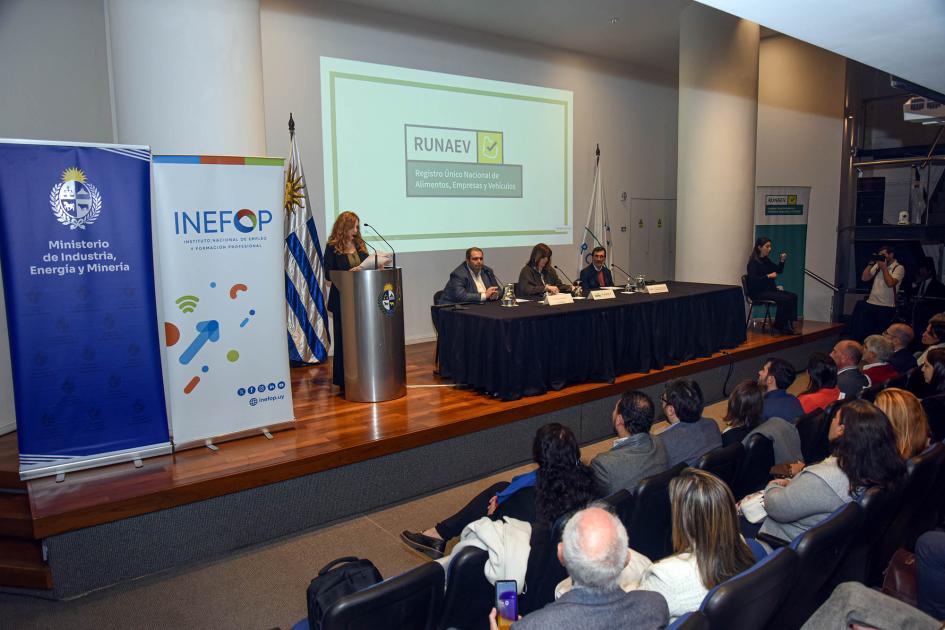 Miguel Venturiello, Antonella Goyeneche y Wilson Aparicio Ezquerra Escenario donde se encuentra mesa con autoridades, banner institucionales y maestra de ceremonia