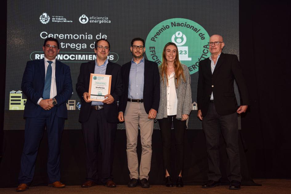 Representantes de Urufarma Cantero, tres hombres (uno sostiene una placa) y una mujer; detrás hay una placa