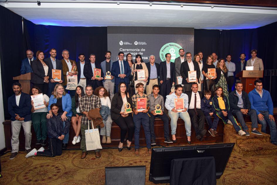 Ganadores de los reconocimientos del Premio Nacional de Eficiencia Energética 2023 y autoridades Todos quienes recibieron premios y autoridades posan para la foto en un escenario con una pantalla