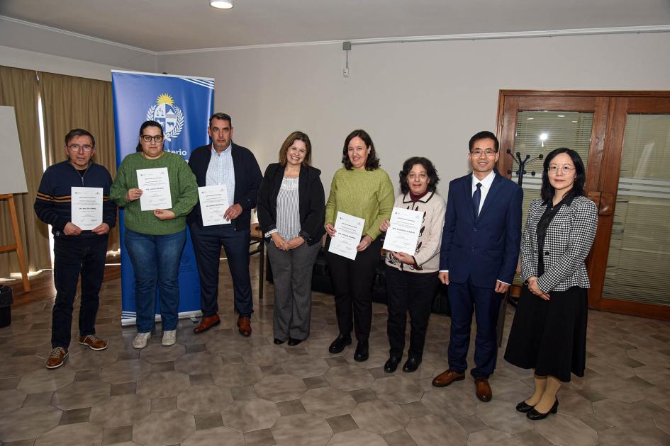 Participantes del taller Ocho personas paradas junto a un banner institucional muestran sus certificados