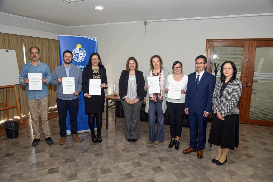 Participantes del taller Ocho personas paradas junto a un banner institucional muestran sus certificados