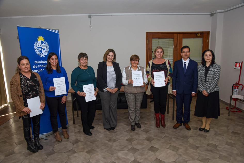 Participantes del taller Ocho personas paradas junto a un banner institucional muestran sus certificados