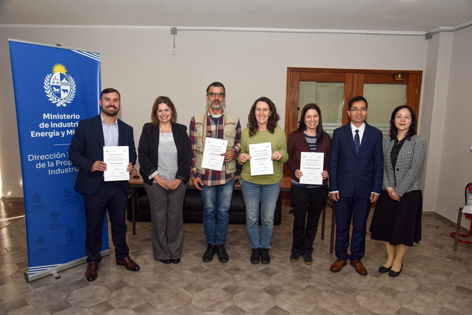 Participantes del taller Siete personas paradas junto a un banner institucional muestran sus certificados