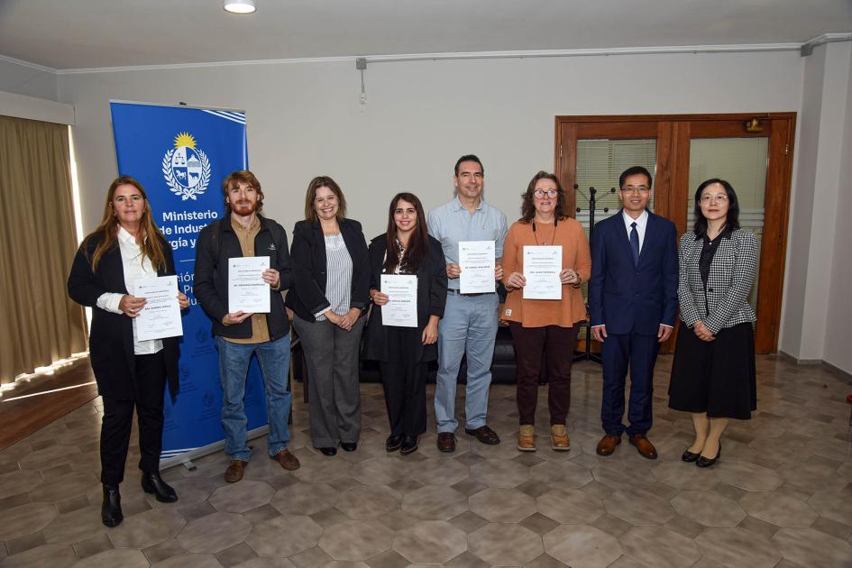 Participantes del taller Ocho personas paradas junto a un banner institucional muestran sus certificados