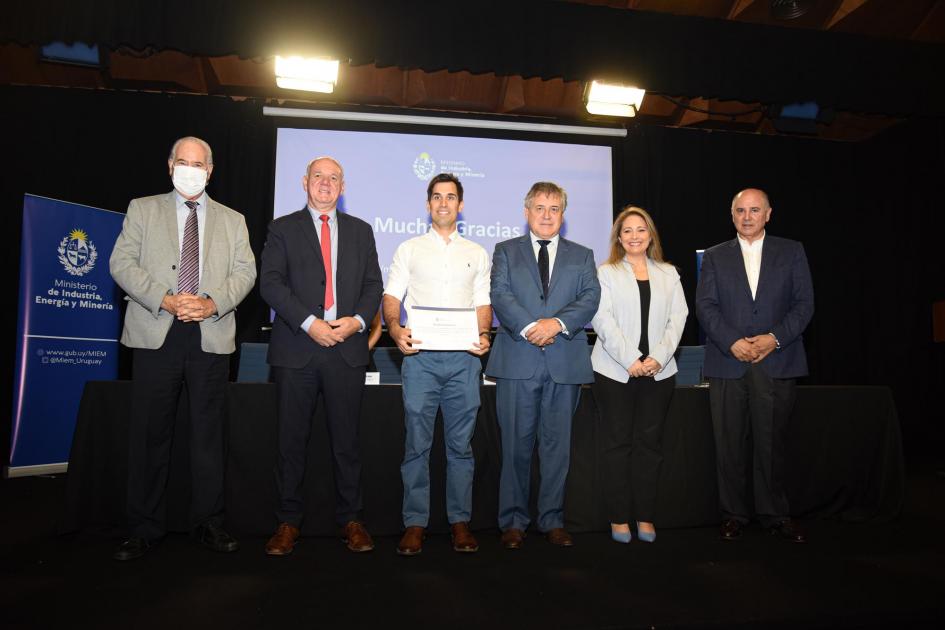 Certificado para Valetor SA Un hombre muestra su certificado junto a las autoridades; detrás, una pantalla azul