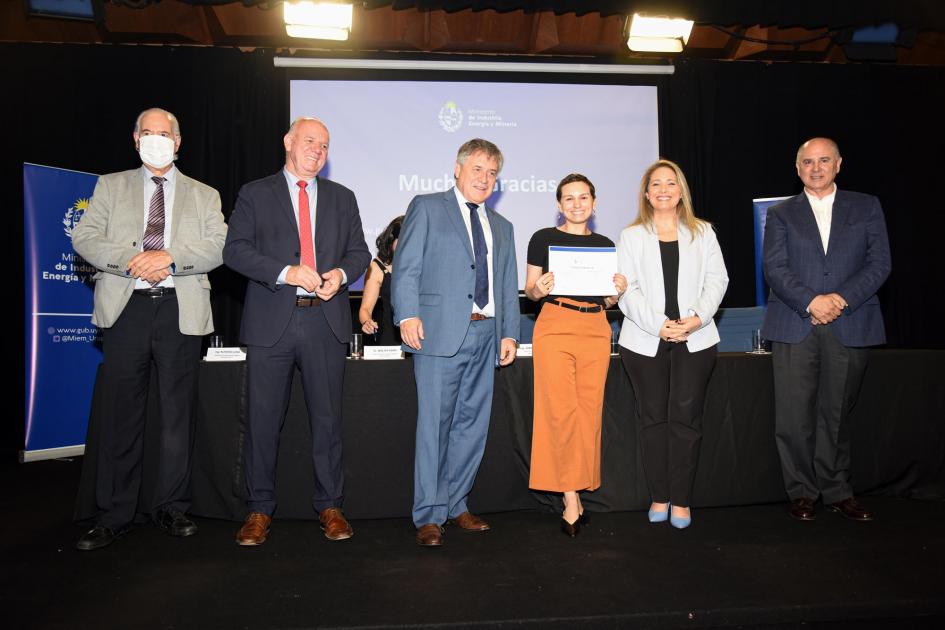 Certificado para Brotzeit, Panadería Alemana Una mujer muestra su certificado junto a las autoridades; detrás, una pantalla azul