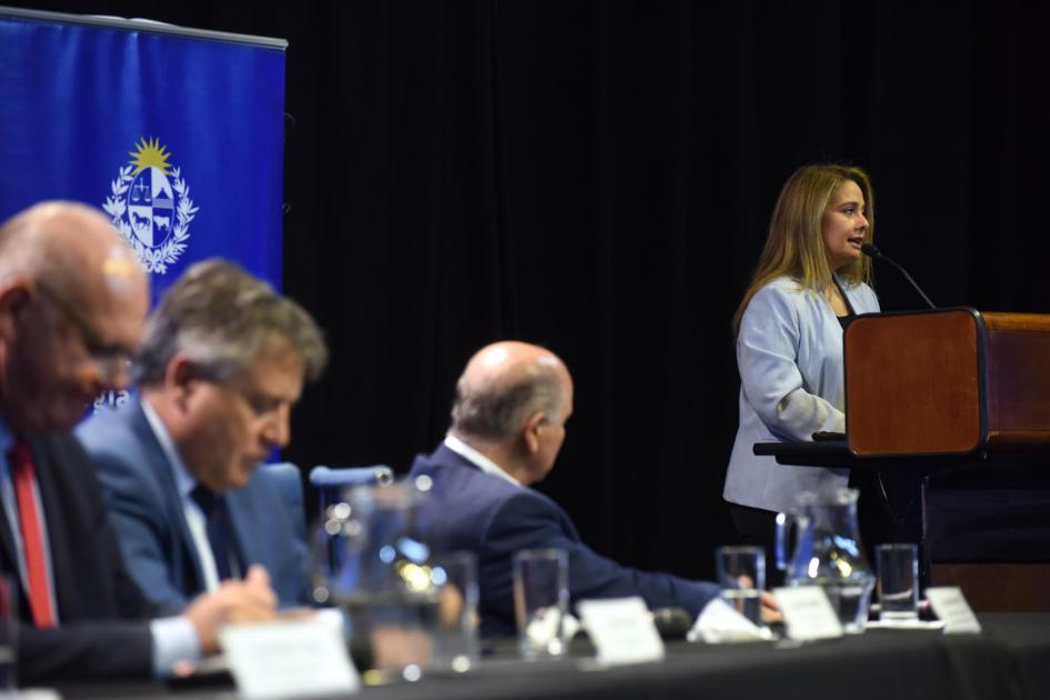 La directora Susana Pecoy cerró la oratoria del evento Directora Pecoy habla desde un atril; a su lado, un banner del MIEM, y luego, mesa de autoridades