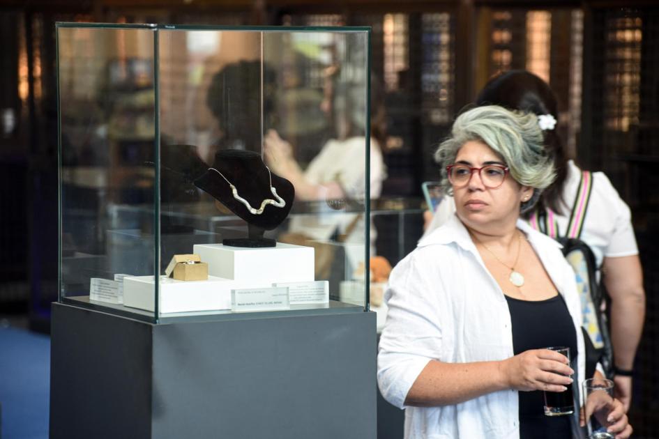 Una mujer está junto a una pieza: un collar en la caja de cristal