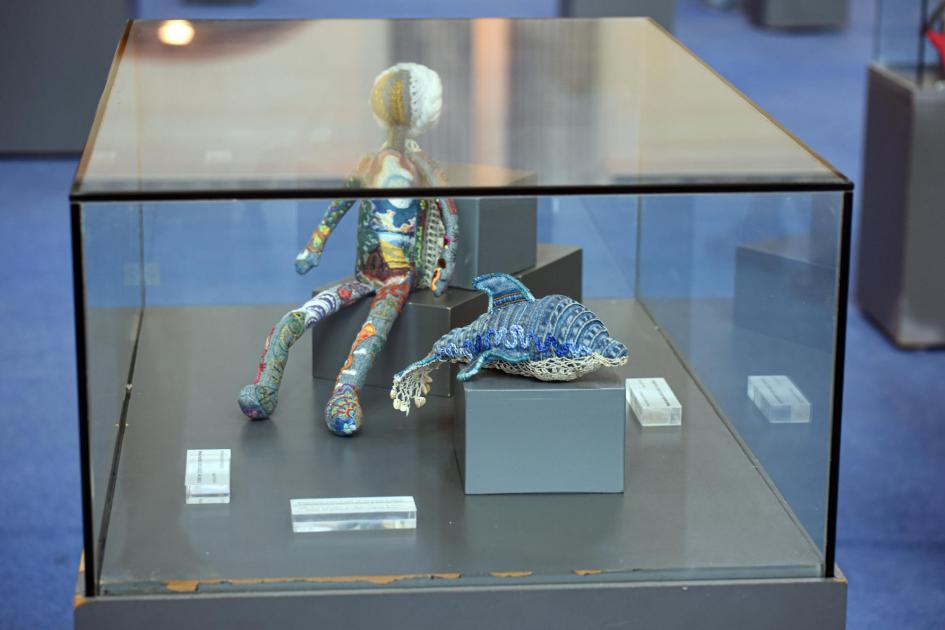 Muñeco y delfín hechos de tela, dentro de una caja de cristal
