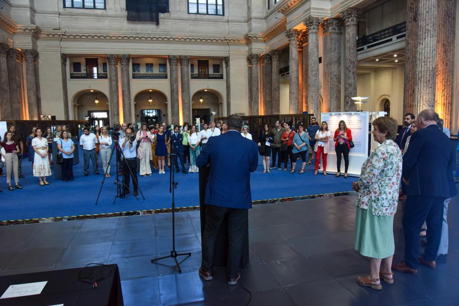 Vista del hall del BROU; se ve la exposición y el público desde detrás del orador, Lafluf