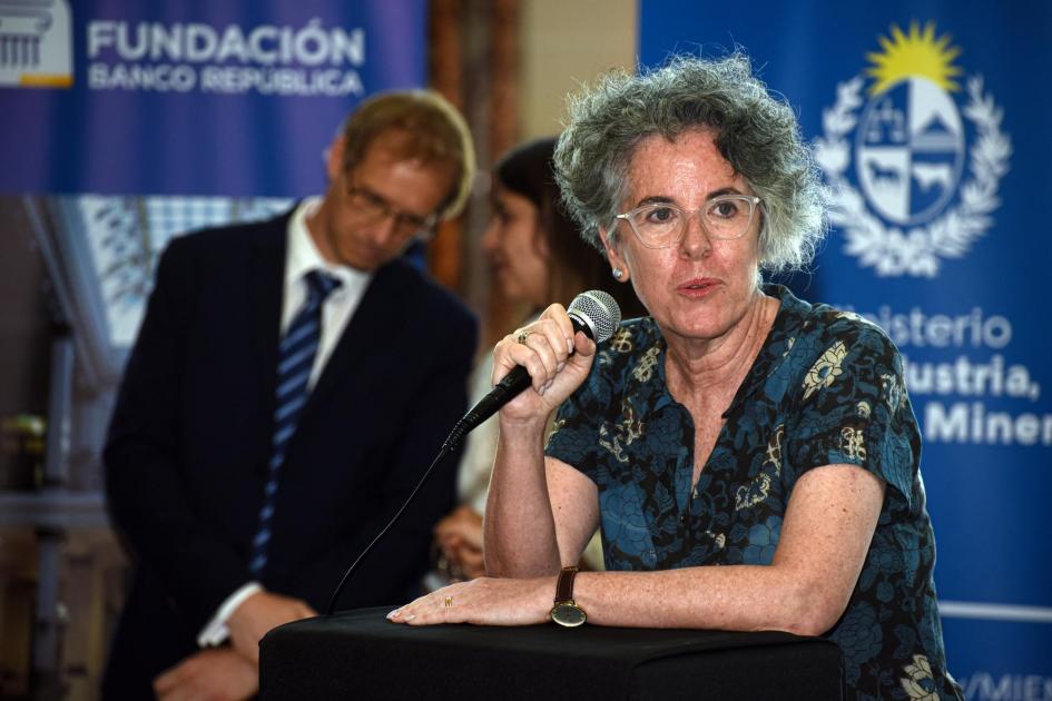 Directora nacional de Cultura, Mariana Wainstein Habla la directora de Cultura, Mariana Wainstein; detrás dialogan dos personas y hay banner del MIEM