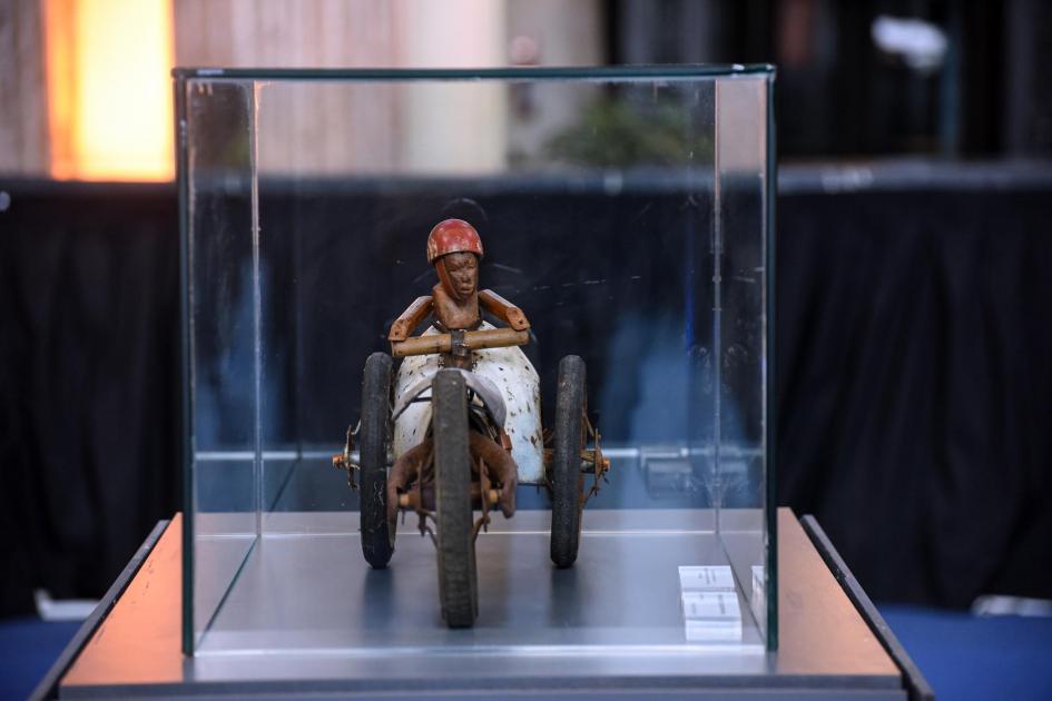 Figura de motociclista que parece de época, en una caja de cristal