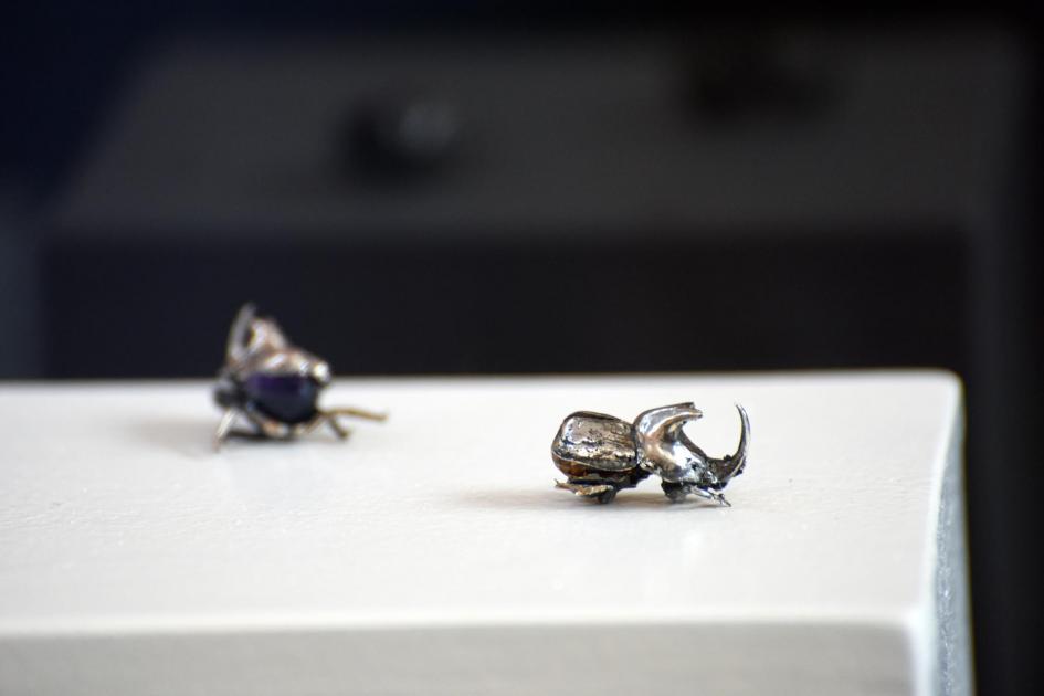 Escarabajos de metal en una superficie blanca