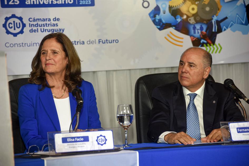 Ministra Elisa Facio y presidente de la CIU, Fernando Pache Facio y Pache, sentados en una mesa; detrás, un logo de la CIU