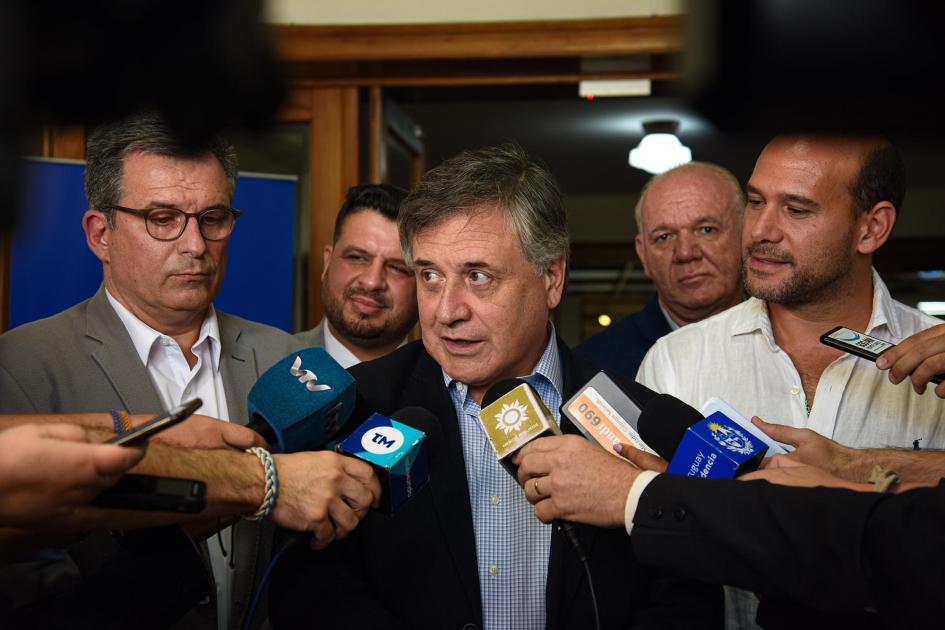 El ministro Omar Paganini abrió la rueda de prensa Ministro Omar Paganini habla, rodeado de micrófonos, junto a Lema, Stipanicic, Verri y Durand