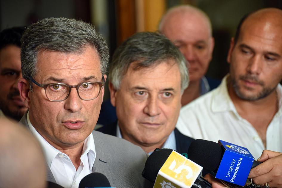 El presidente de Ancap dijo que las finanzas de Ancap permiten extender el subsidio Stipanicic habla, rodeado de micrófonos; a su lado, Paganini y, luego, Lema; detrás, Durand y Verri