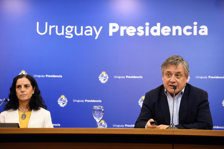 Ministro Paganini junto a ministra Arbeleche; detrás, banner azul de Presidencia