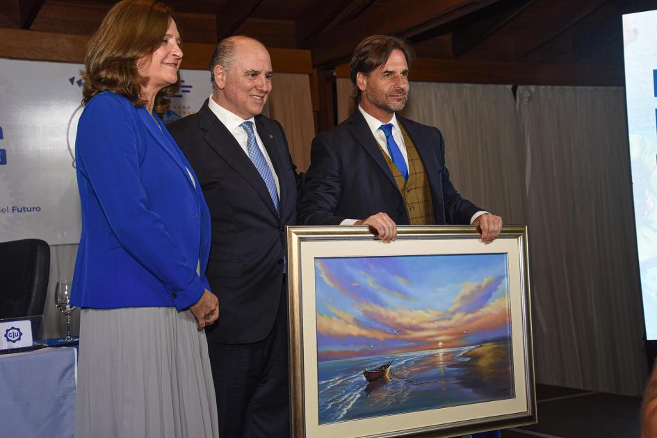 Presidente Luis Lacalle Pou; ministra Elisa Facio; presidente de la CIU, Fernando Pache Facio, Pache y Lacalle Pou, de pie; el último sostiene un cuadro